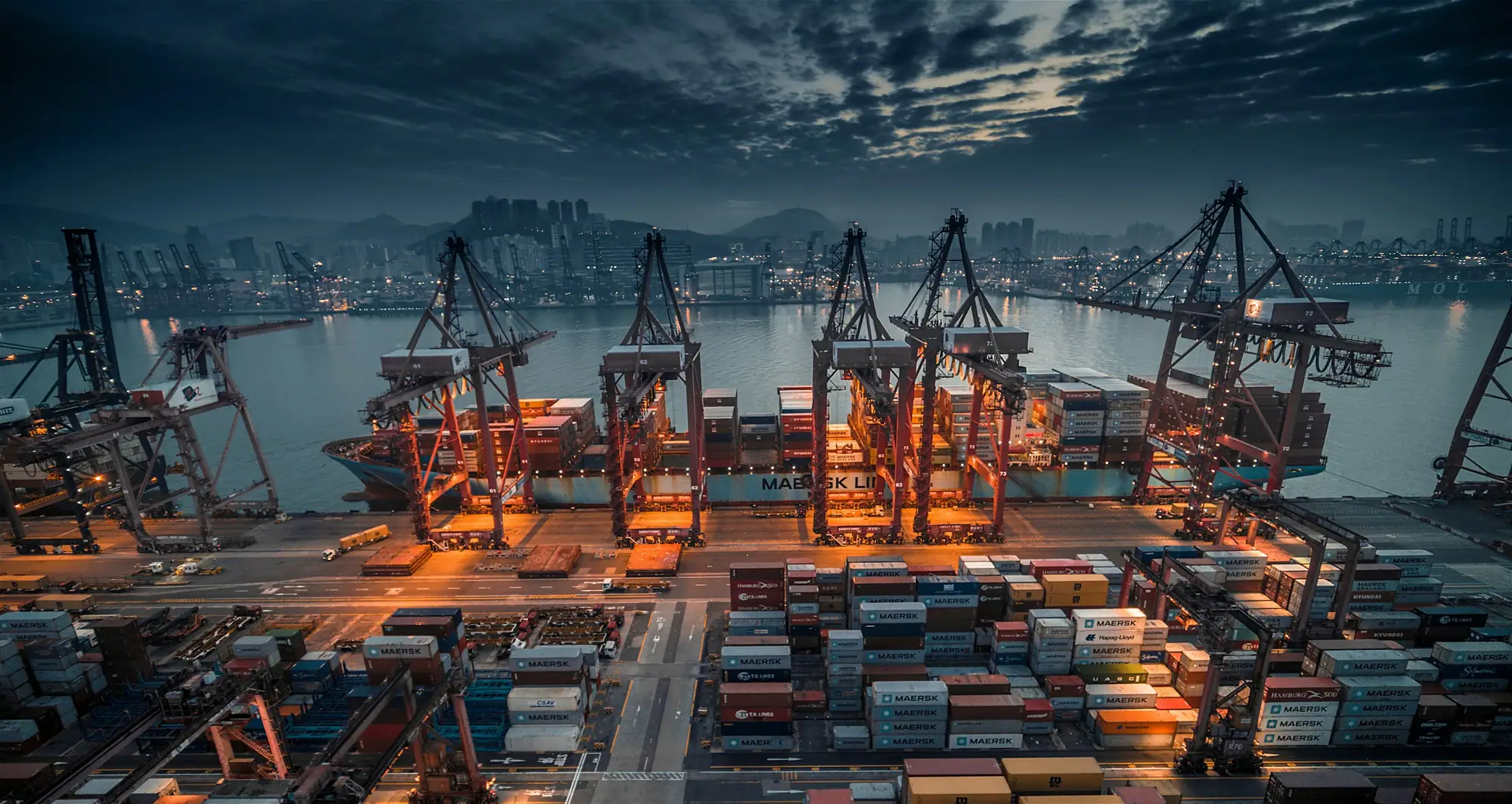 Container port and city skyline at dusk